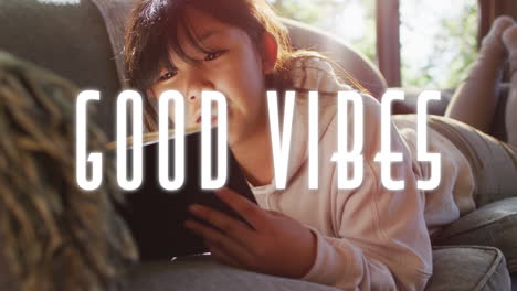 animation of good vibes text over asian girl using tablet