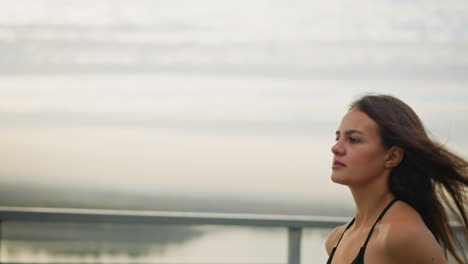 young woman in black singlet running outdoors along path with blurred background, determined expression and movement, capturing her focus and energy as she enjoys her fitness routine