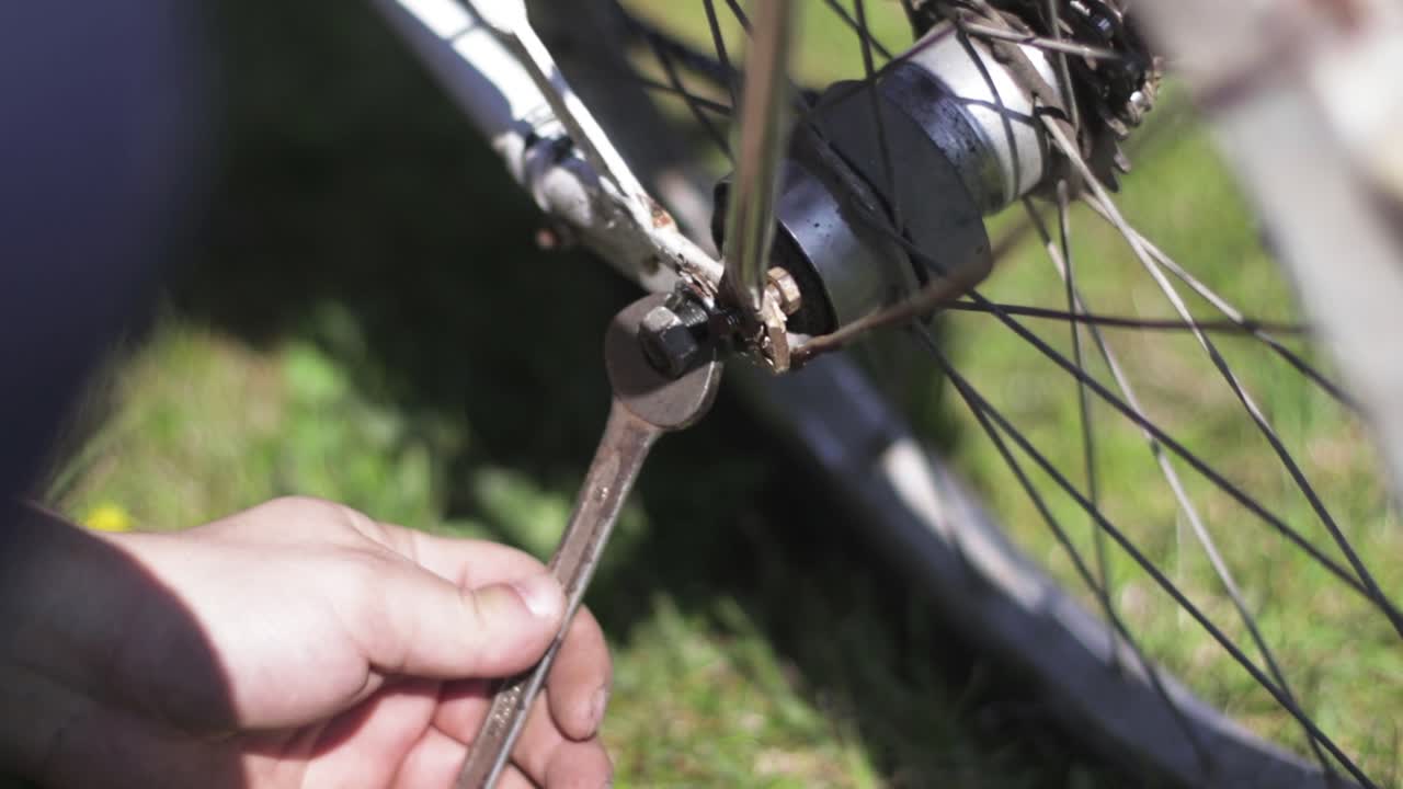 Fixing a broken bicycle. Screwing a screw with a wrench. Mechanic using a wrench to fix a bike.