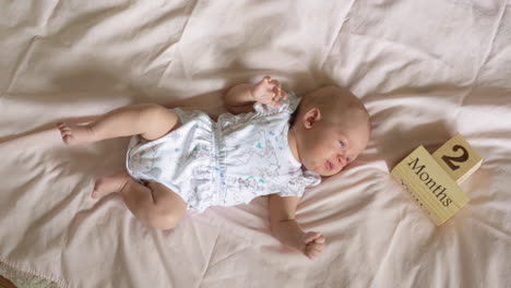 a two months old baby lying on a bed