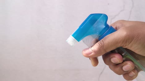 mano con una botella de spray azul