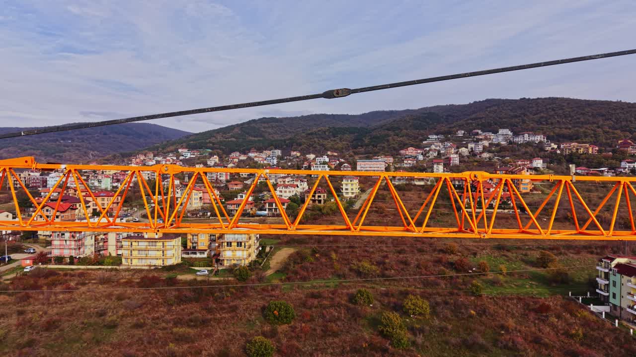 Vista aerea di una gru edile arancione che sovrasta un villaggio di montagna