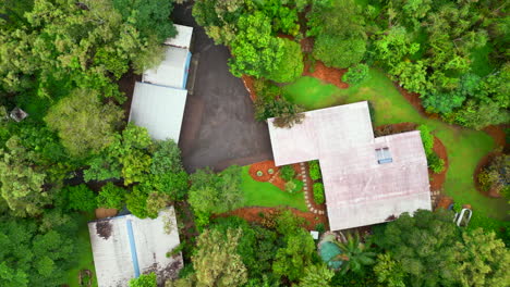 Drones-Aéreos-Del-Exterior-De-Una-Casa-Tropical-Tupida-En-Un-Día-Lluvioso-Ascienden-Para-Establecer-Una-Propiedad-De-Exuberante-Selva-Verde