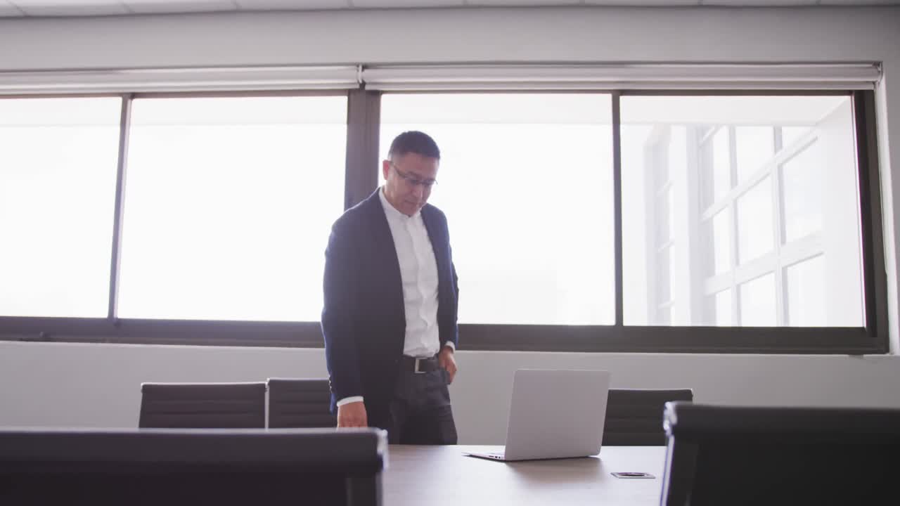 hombre de negocios sénior usando una computadora portátil mientras está de pie en una oficina moderna en cámara lenta