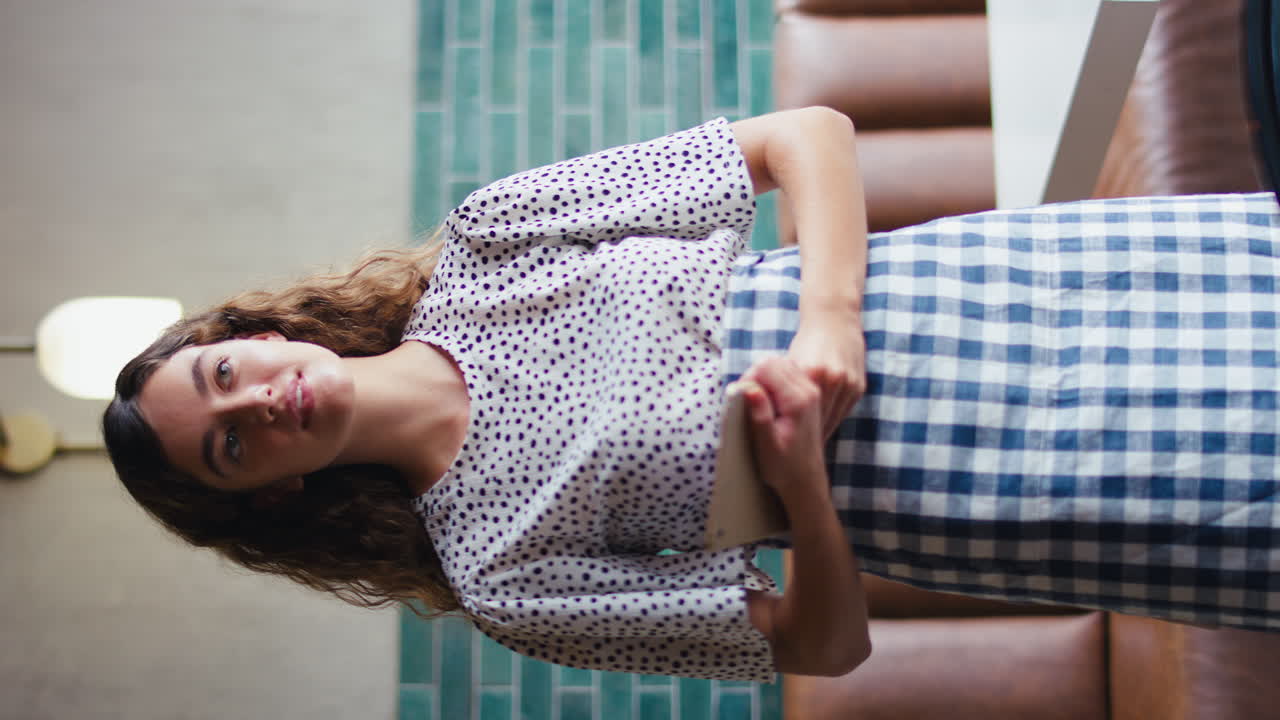 retrato de video vertical de una dueña o personal sonriente con una tableta digital trabajando en una cafetería