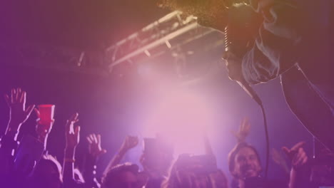 male performer leaning toward fans in music concert, showing animated smartphone icons
