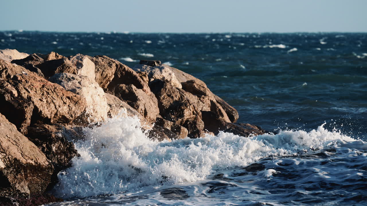 Primo piano di onde oceaniche che si infrangono contro grandi rocce costiere