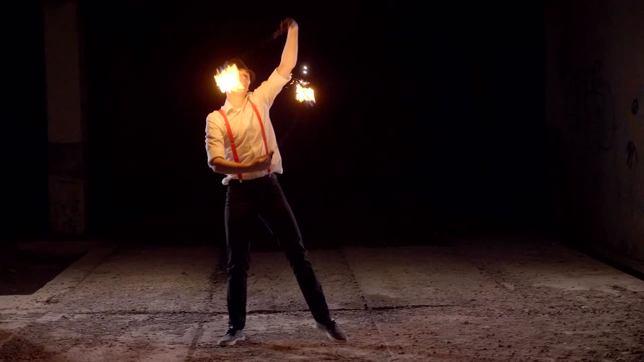 artista masculino realizando un espectáculo de fuego en la oscuridad en cámara lenta.