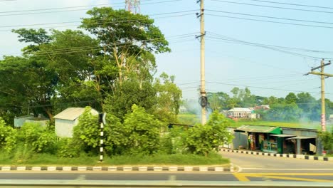 traveling through smoky fields and past roadside shops in a rural area, along the dhaka-barisal mawa road in bangladesh - pov shot