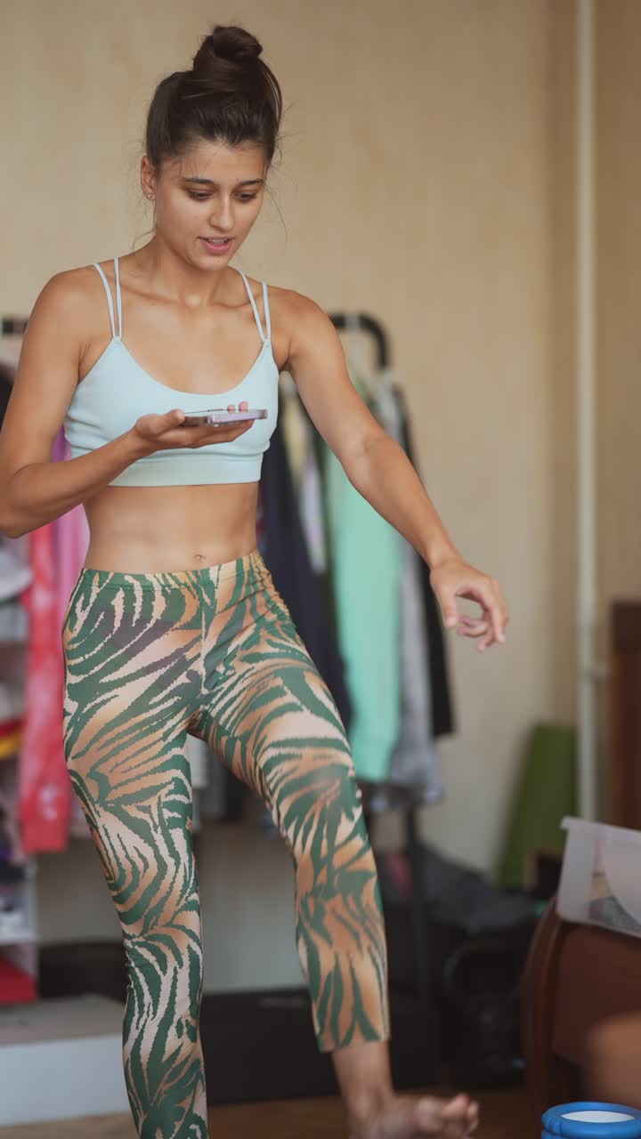 mujer haciendo ejercicio de yoga en casa usando teléfono móvil