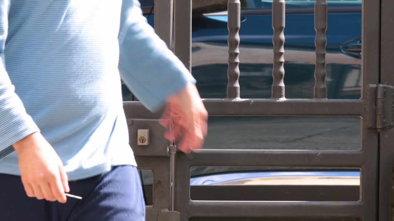 열쇠를 사용하여 야외에서 검은 강철 문의 자물쇠를 여는 젊은 남자 드레싱 피자마