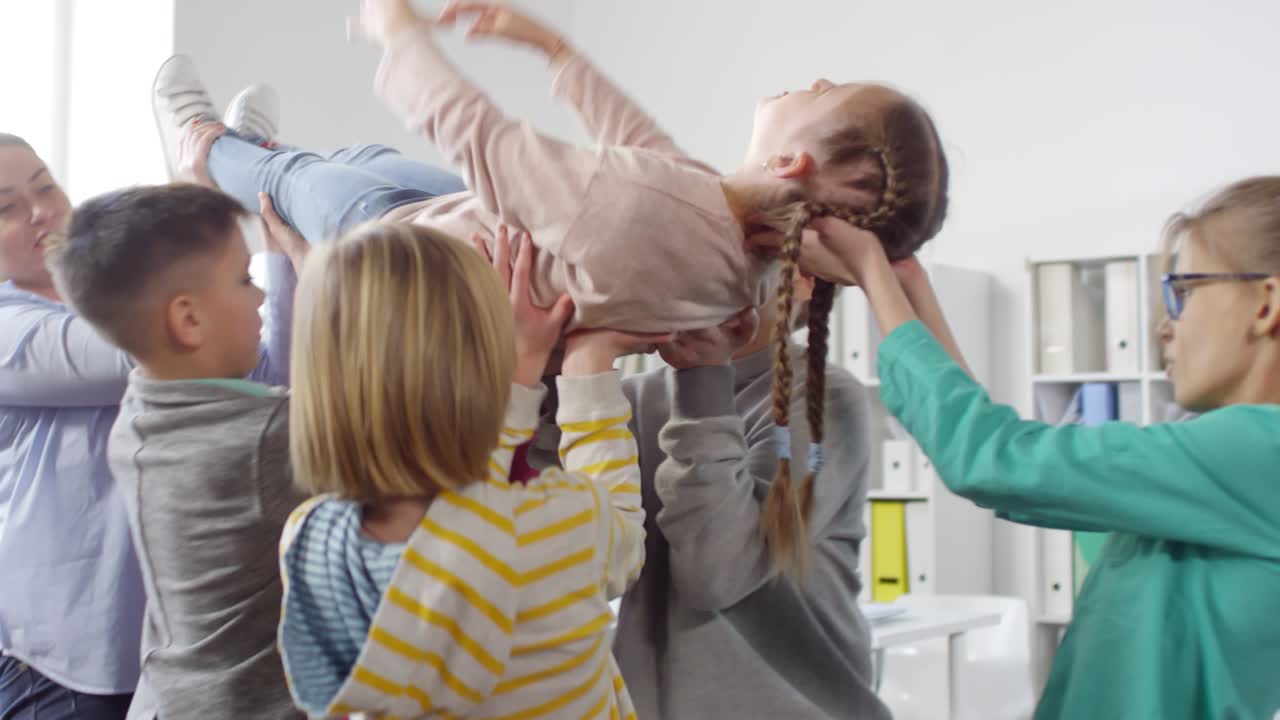 Group of Kids and Woman Lifting Girl Up in Air