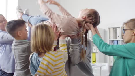 group of kids and woman lifting girl up in air