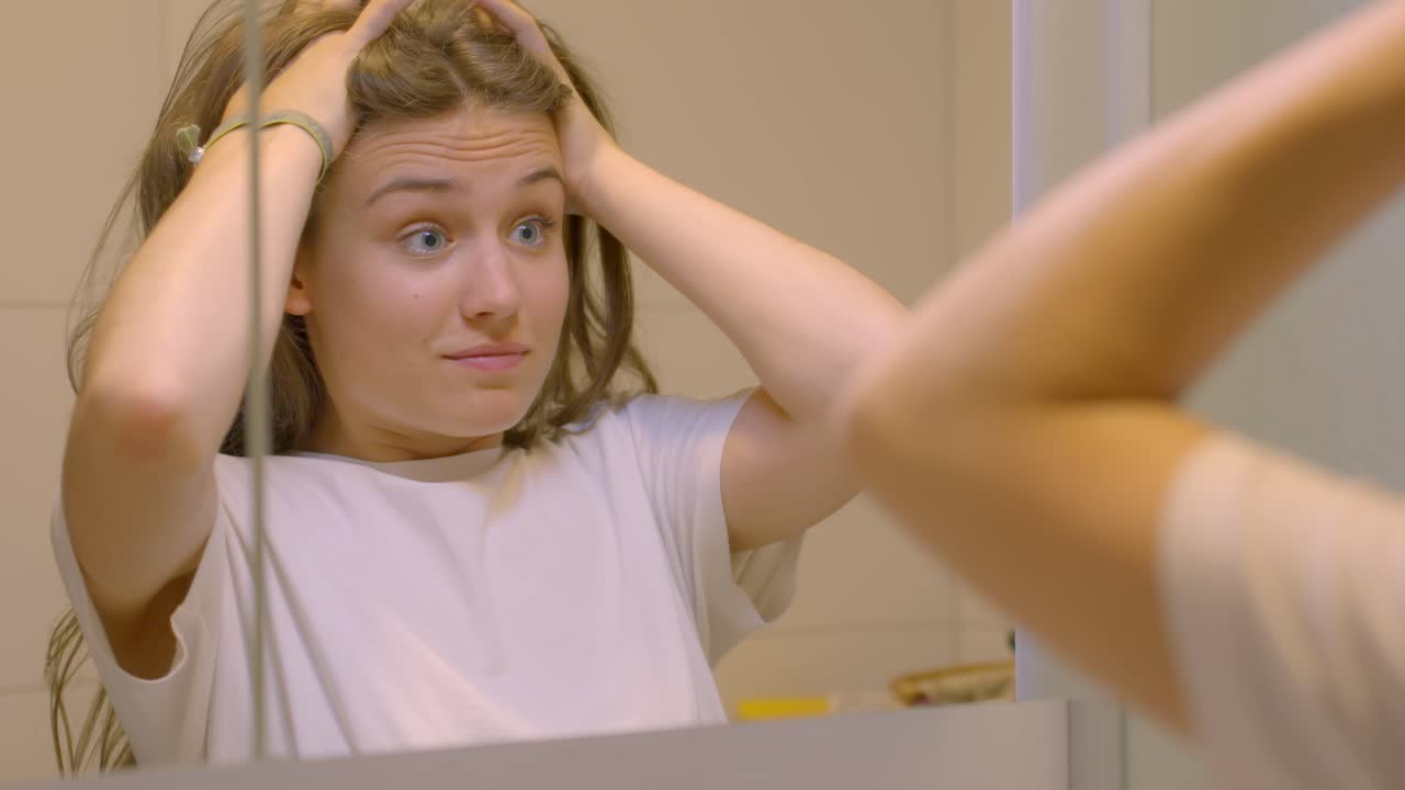 젊은 갈색 여성이 화장실 거울에서 긴장하고 걱정하고, 느린 움직임으로