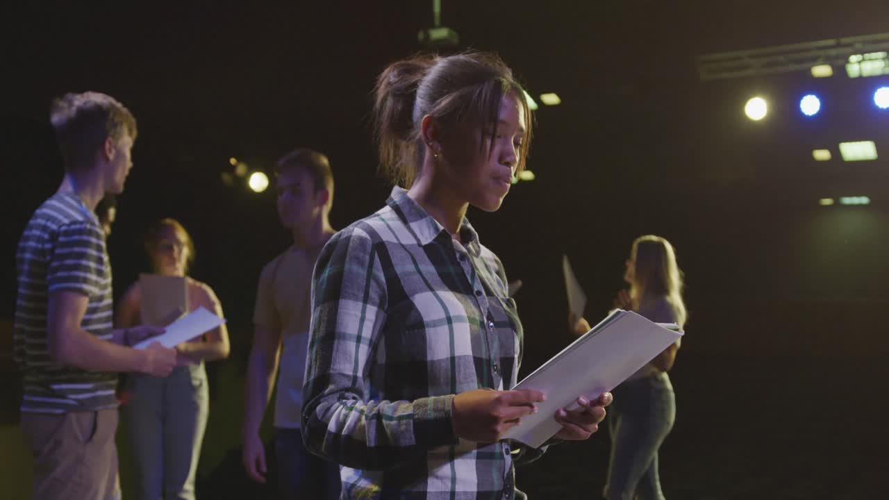 Students preparing before a high school performance in an empty school theater