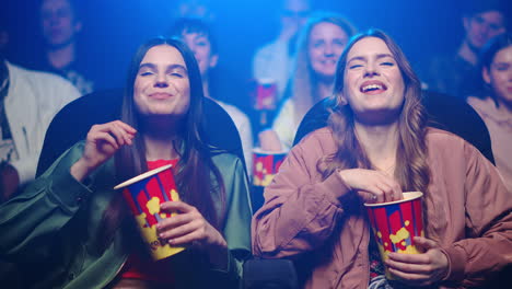 happy women eating popcorn in movie theater