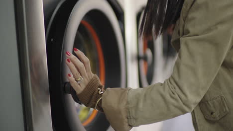 a contemporary woman with crimson nails begins her laundry routine by shutting the washing machine door