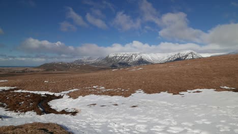 mountains and grassland partially covered in snow in early spring