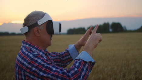 un agricultor adulto usa la realidad virtual para la agricultura sosteniendo una espiga en sus manos y presionando su dedo en el grano utilizando tecnología y gráficos modernos.