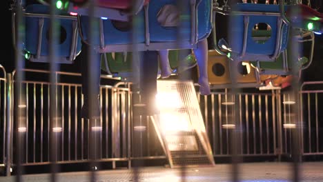 Father-and-daughter-legs-waiting-on-a-colorful-carousel-swing-seats-at-night-in-a-park