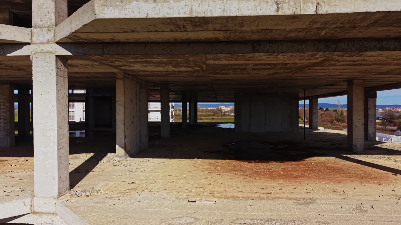 Abandoned building under construction near greenhouses and fields