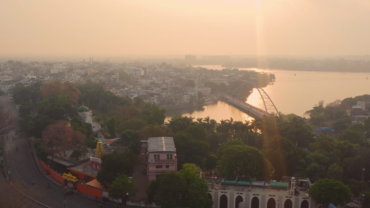 Aerial View of a Hazy City with a River and Arch Bridge at Sunset