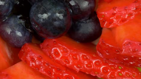 macro shot of some glazed blueberries and sliced strawberries rotating