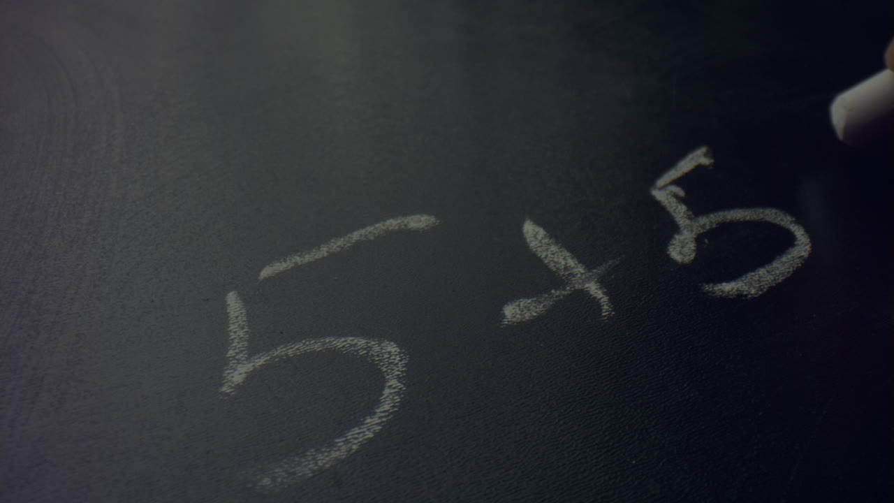Woman hand holding piece of chalk. Unknown female person writing on blackboard