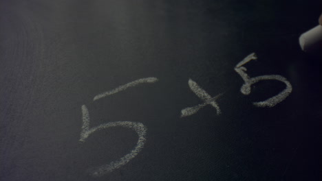 Woman-hand-holding-piece-of-chalk.-Unknown-female-person-writing-on-blackboard