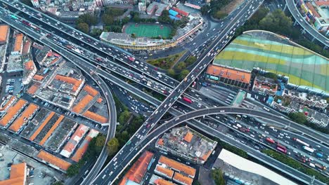 drone shot of a busy highway intersection cutting through an urban landscape during rush hour. the contrast between city infrastructure, industrial buildings, and green spaces. guangzhou, china.