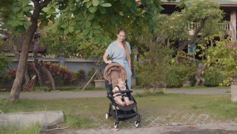 madre empujando el cochecito con el bebé feliz