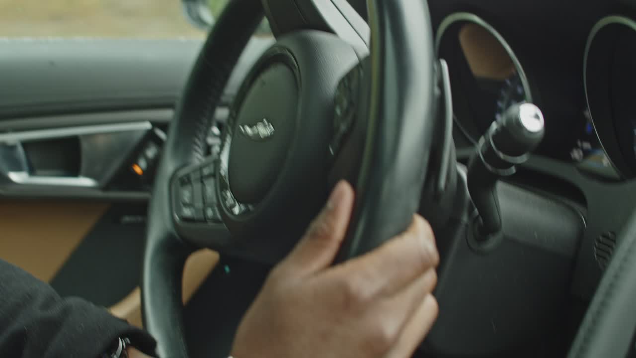 manos en el volante de un coche deportivo de lujo conduciendo rápido