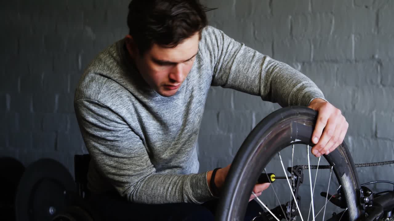 Man met een beperking die een rolstoel repareert in een werkplaats 4k