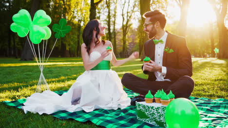 joyful couple shares green cupcakes in a park