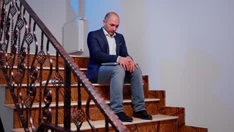 stressed businessman closing laptop sighing sitting on stairs