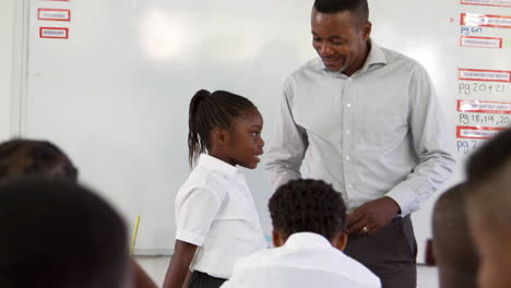 teacher and schoolgirl in front of elementary school class