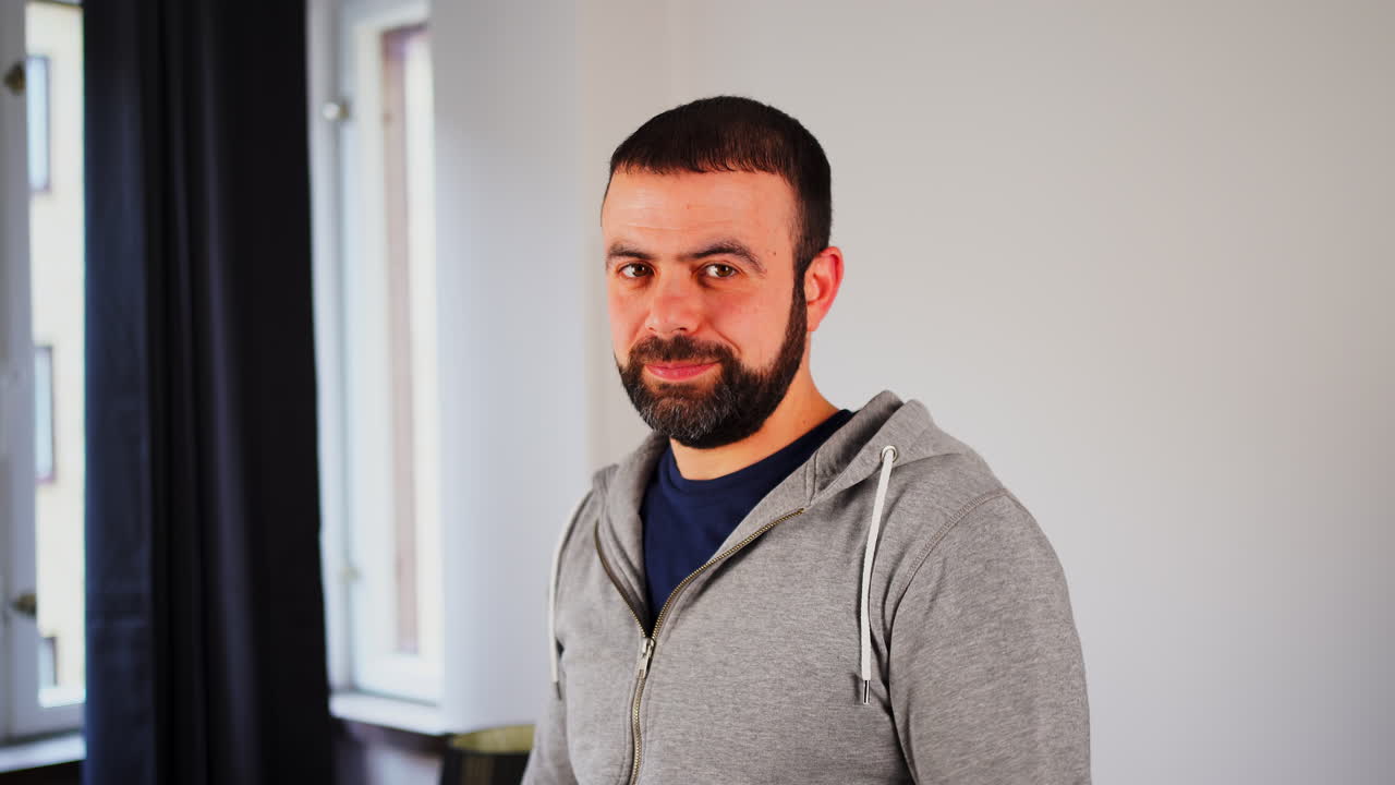 hombre caucásico del este medio haciendo gestos con los pulgares hacia abajo en la casa