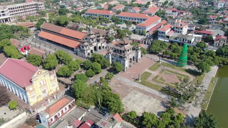 Vista-Aérea-De-Drones-En-Vietnam-Dando-Vueltas-Sobre-Un-Templo-De-Piedra-En-Ninh-Binh-En-Una-Ciudad-Con-Edificios-Con-Techo-De-Ladrillo-En-Un-Día-Soleado