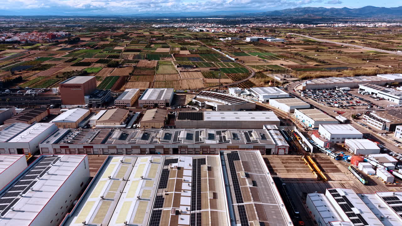 Madrid, Espanha, 8 de agosto de 2025: Vista aérea de armazéns em parque industrial e campos agrícolas. Tomada aérea de edifícios fabris com painéis solares, lotes de terras agrícolas verdes, trilhos ferroviários.