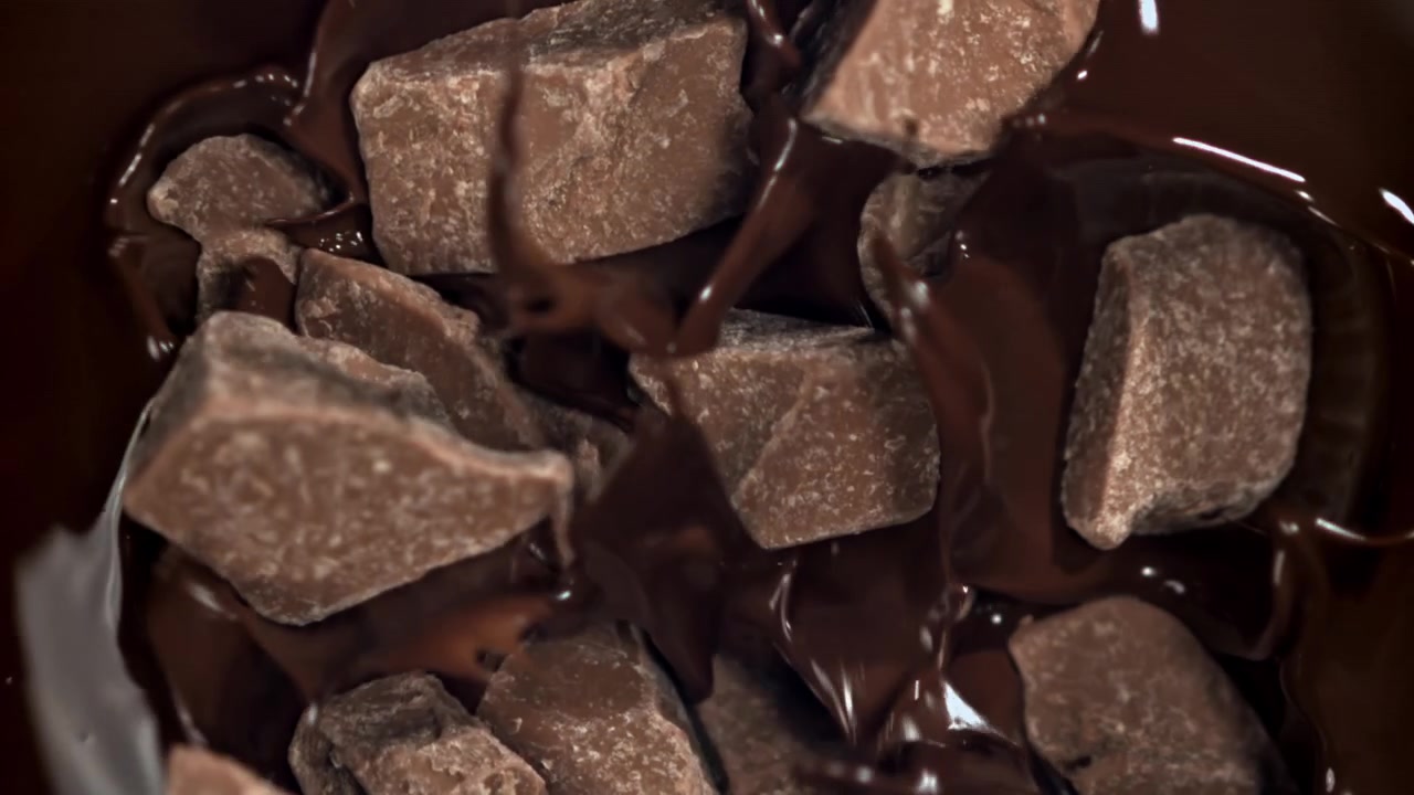 Super rallentatore di cioccolato fuso che cola su pezzi di cioccolato