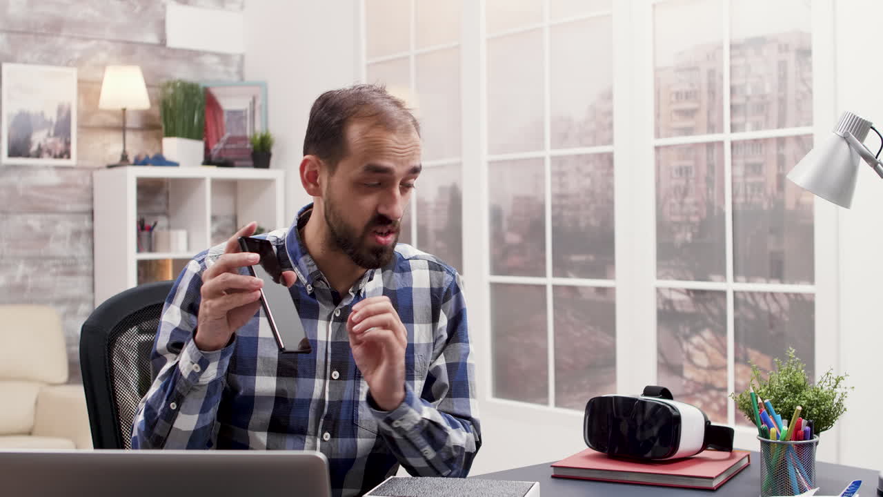 Man unpacking smartphone in home office