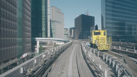 a point-of-view shot of the yurikamome monorail slowing moving between skyscrapers in tokyo, japan