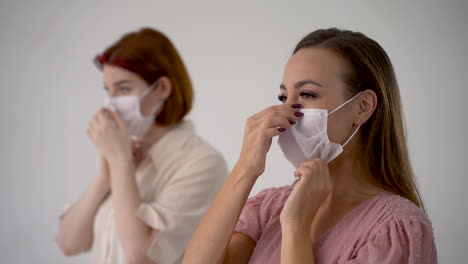 portrait of two women putting on medical face mask. social distancing concept. close-up.