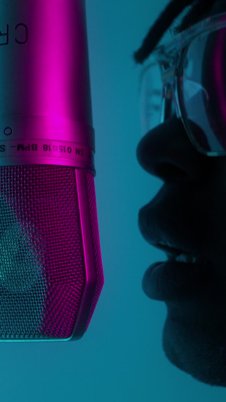 Close-up of a person singing into a microphone in a recording studio.