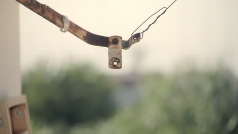 a piece of rusted metal hanging from a wire, gently shaken by the wind