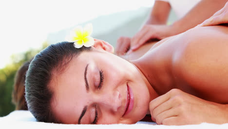 Smiling-brunette-enjoying-a-massage-poolside