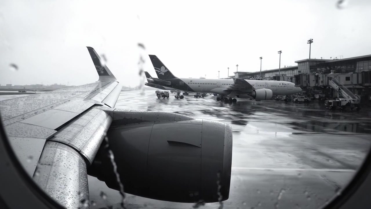 Uno Sguardo Attraverso il Finestrino Piovoso di un Aereo all'Aeroporto, Catturando la Serenità del Piazzale con Aerei Parcheggiati in Attesa del Loro Prossimo Viaggio