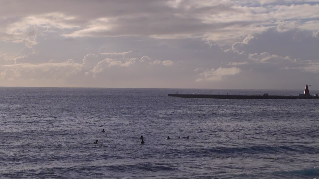 vista de silueta de un grupo de surfistas esperando olas en el océano en un día brillante y soleado, nublado - posibilidad remota