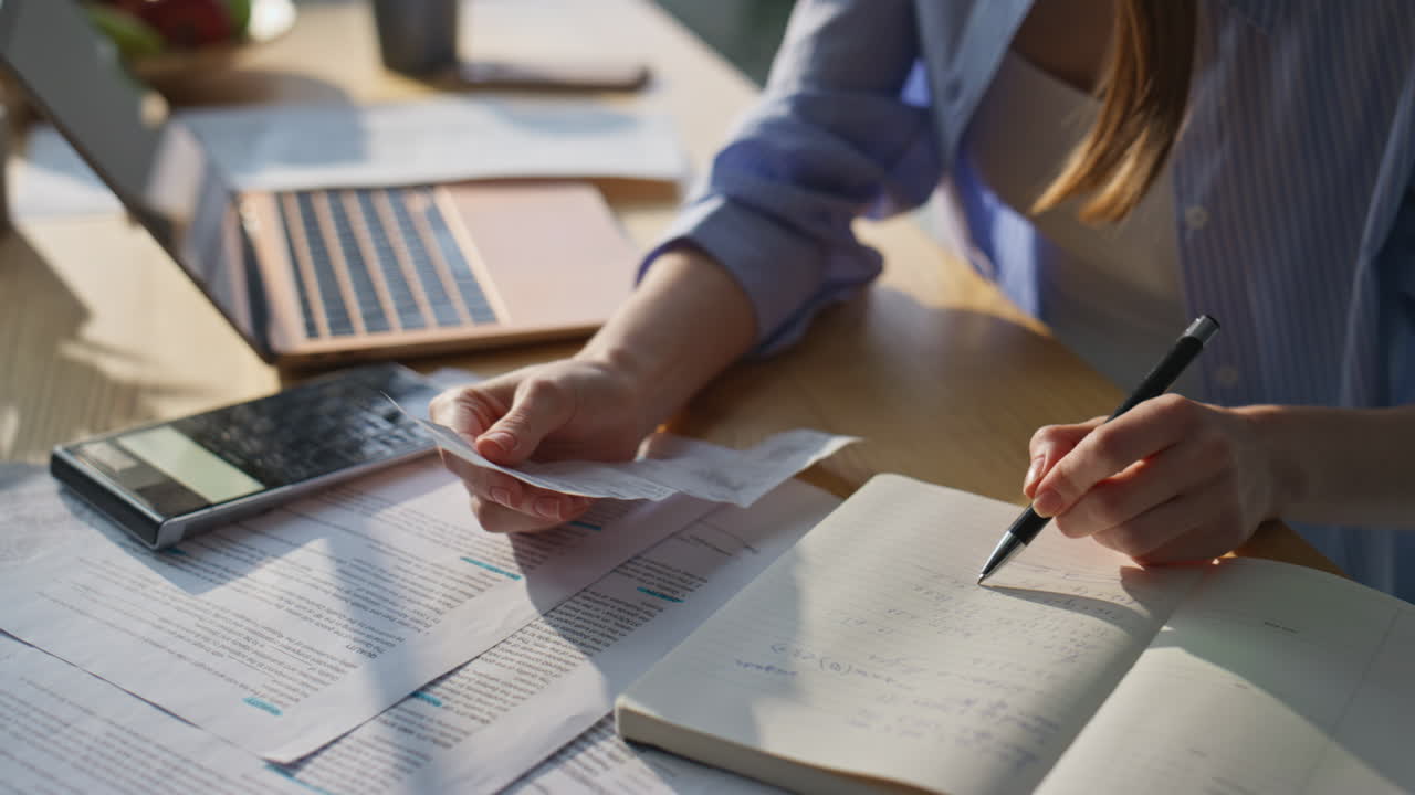 Woman hands calculating finances expenditures checking notes in notebook closeup