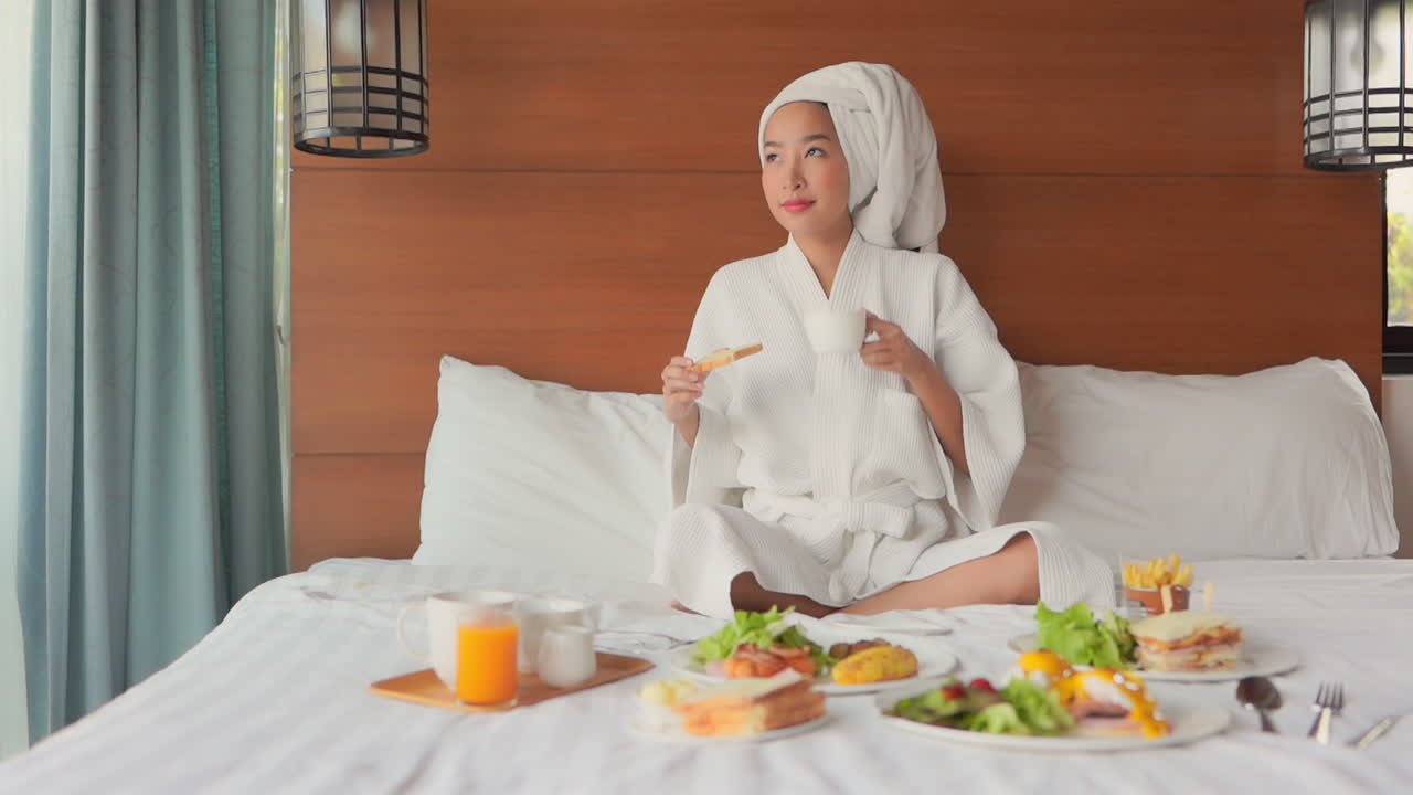 Beautiful smiling woman bathrobe and hair towel taking fresh breakfast in hotel bedroom